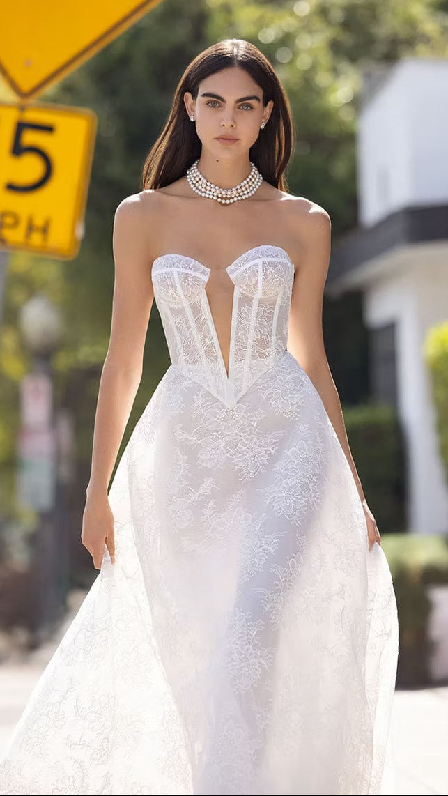 Woman in a white wedding dress standing on a street with traffic signs in the background