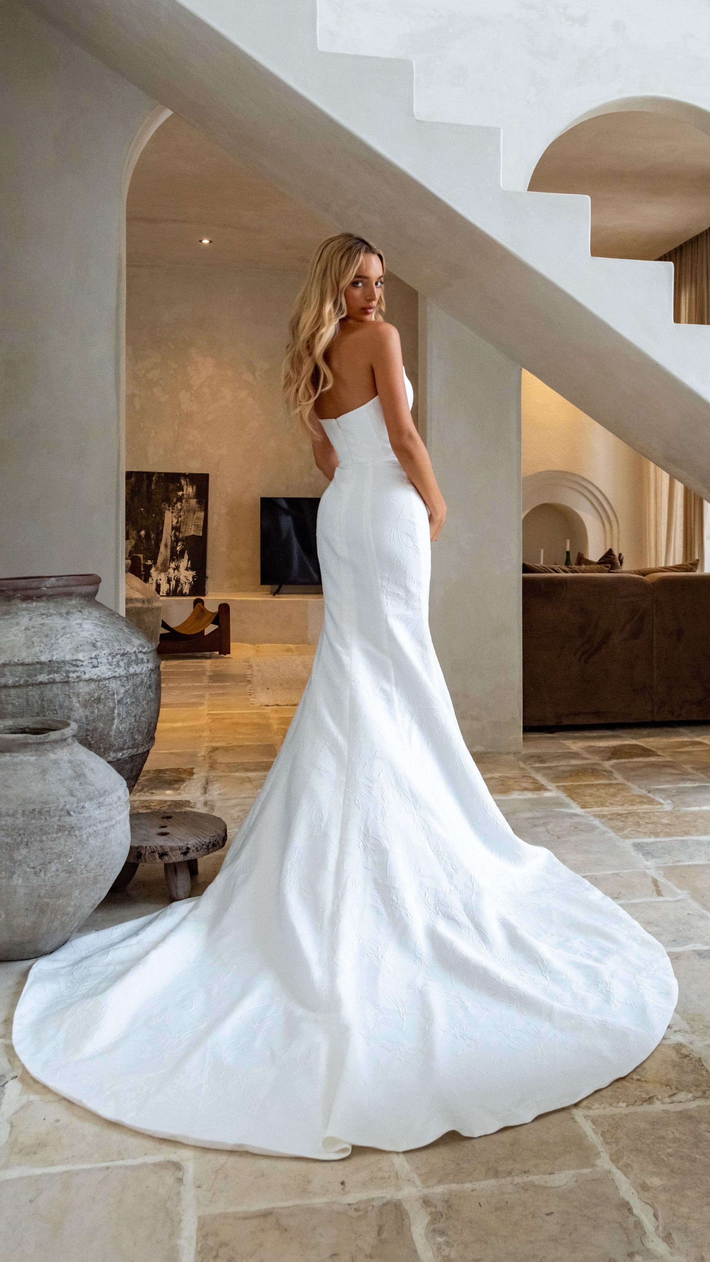 Woman in a white wedding dress standing in a modern interior setting.