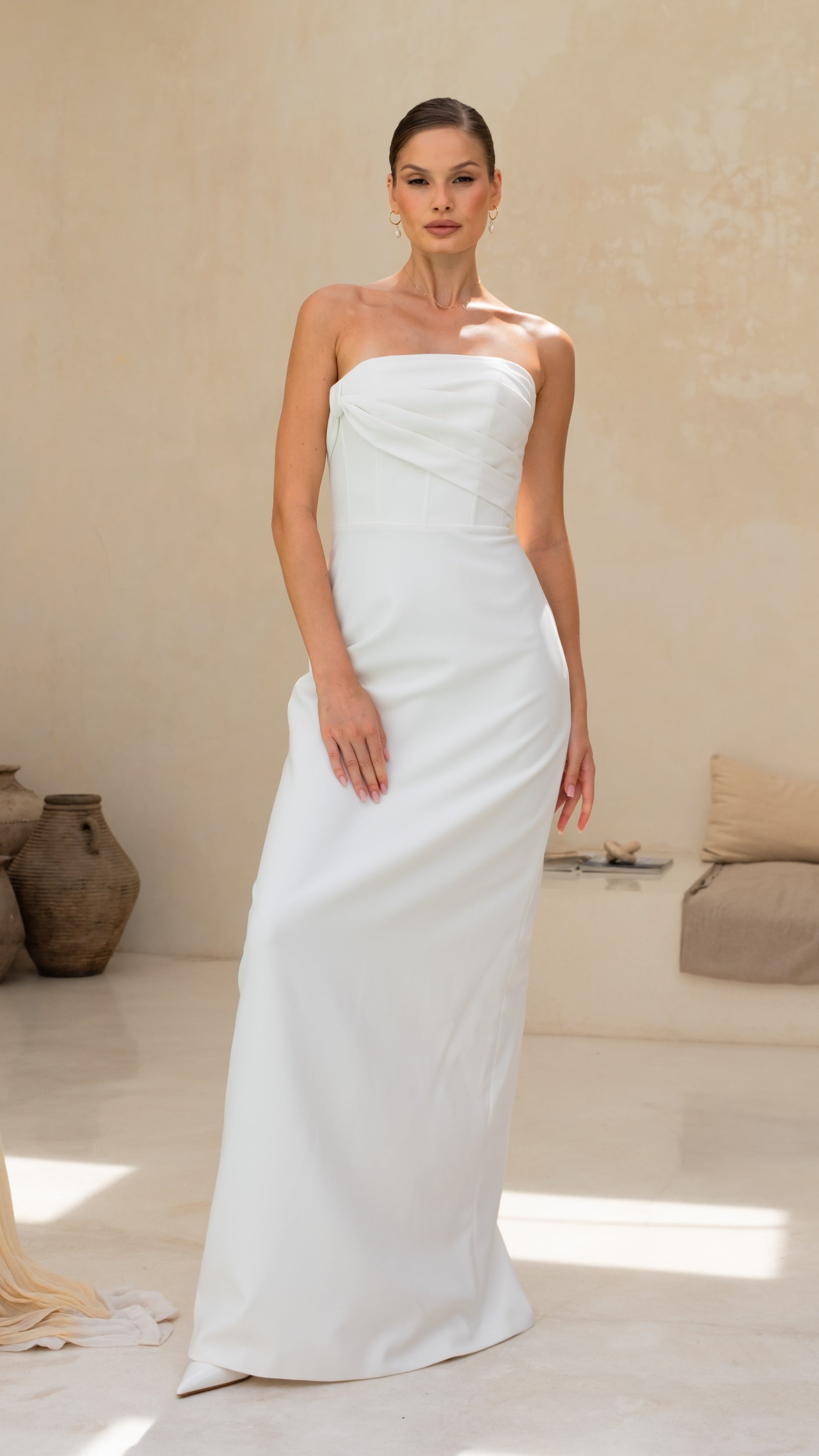 Woman wearing a strapless white wedding dress in a minimalistic room.